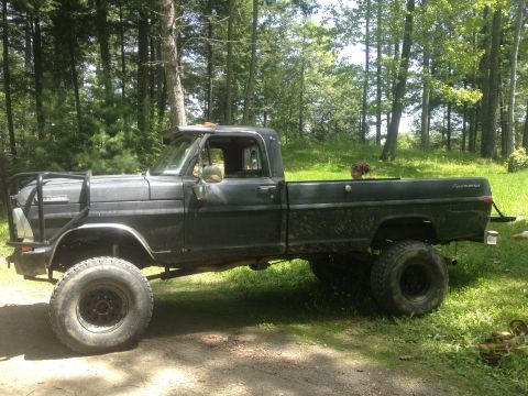 1970 Ford F-250 - This lifted 1970 Ford F-250 pickup truck is parked outdoors with a brush guard and large tires.