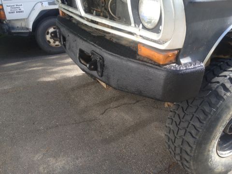 1970 Ford F-250 - The front view of a 1970 Ford F-250 shows its heavy-duty bumper and off-road tire, with another vehicle partially visible in the background.