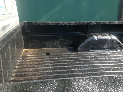 1970 Ford F-250 - Close-up view of a truck bed with a textured spray-in liner and a green wall in the background.