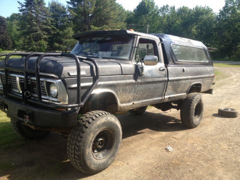 1970 Ford F-250 - This lifted 1970 Ford F-250 pickup truck is equipped with a brush guard and a camper shell.