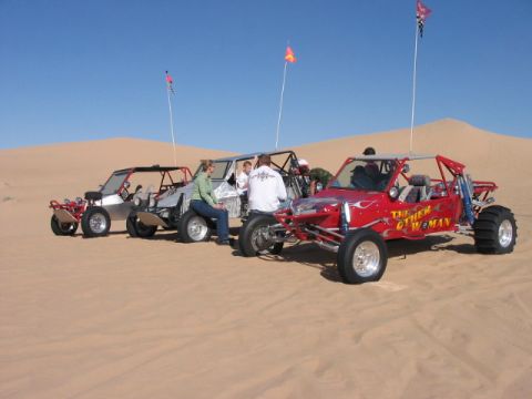 1993 Ford Taurus - Several dune buggies are parked on a sandy desert landscape under a clear blue sky.