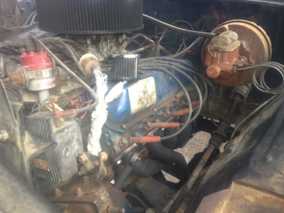 Engine bay with V8 engine, distributor, carburetor, and brake booster visible