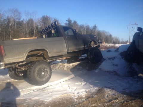 1970 Ford F-250 - A lifted pickup truck with dual rear wheels navigates an off-road course in snowy conditions.