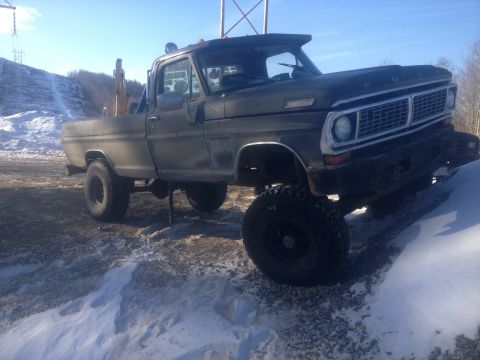 1970 Ford F-250 - This lifted 1970 Ford F-250 pickup truck is parked on a snowy surface under a clear sky.