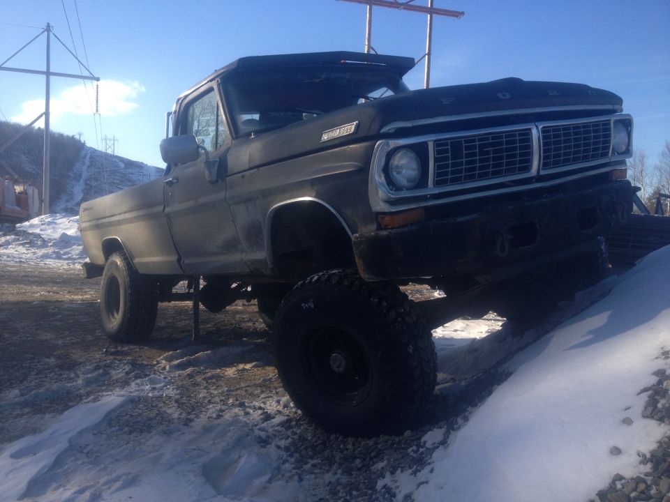 Black Ford pickup truck on snowy ground, front 3/4 view