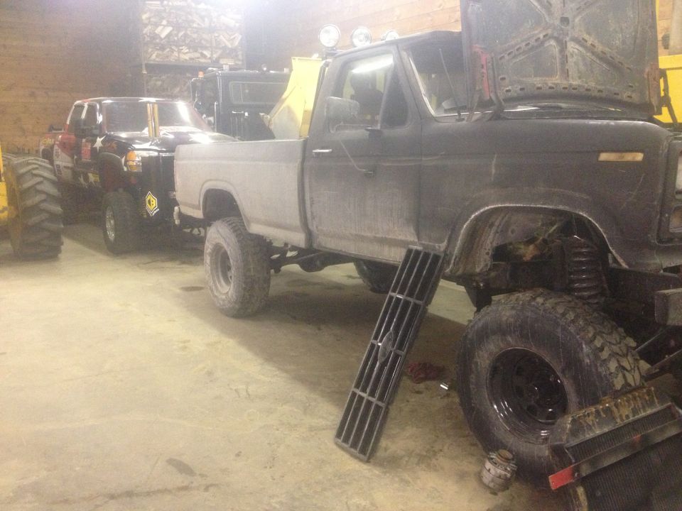 Gray pickup truck with hood open, black pickup truck behind it
