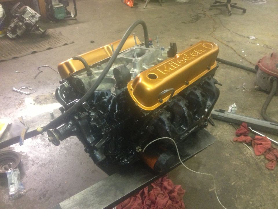 Engine with gold "Kultool" valve covers on a stand in a workshop