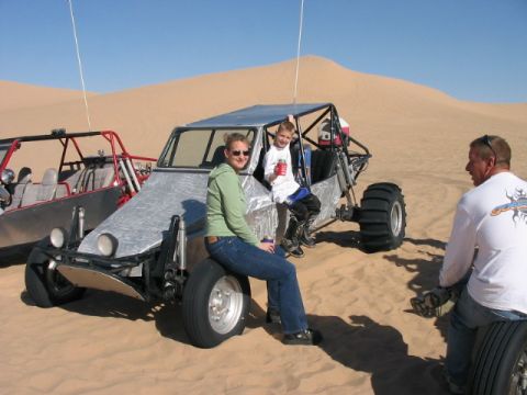 1993 Ford Taurus - People pose with dune buggies in a desert landscape under a clear blue sky.