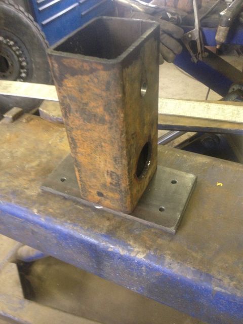 1970 Ford F-250 - A fabricated metal bracket is shown welded to a base plate on a workbench.