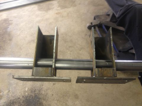 1970 Ford F-250 - Close-up view of custom metal brackets welded onto a metal rod, likely for a vehicle modification.