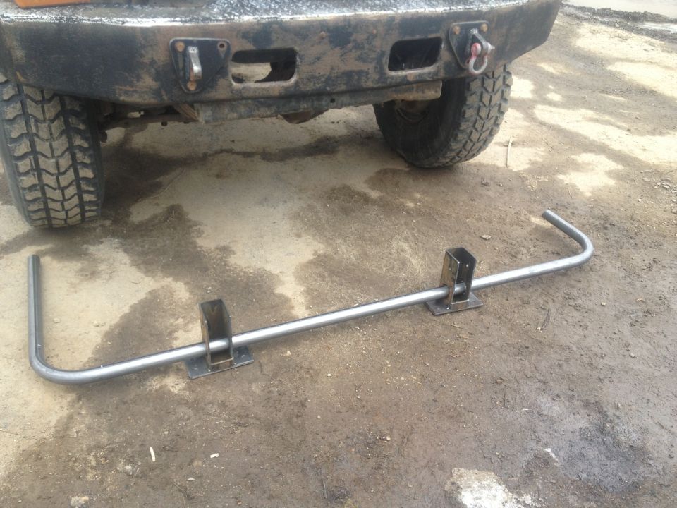 rear of a truck with a custom bumper and a tow hitch assembly lying on the ground in front of it