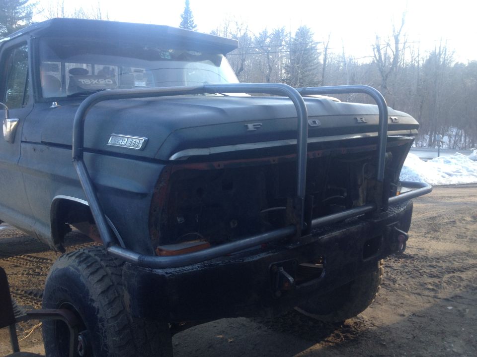 Front view of a dark blue 1970 Ford F-250 with a custom brush guard and missing grille