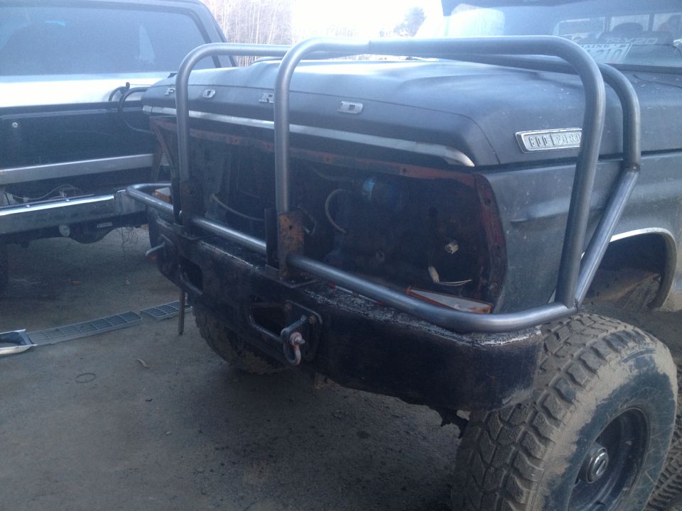 Black 1970 Ford F-250 front end with custom metal bumper and roll cage, missing headlights