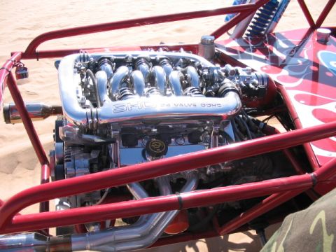 1993 Ford Taurus - A highly polished chrome engine with a prominent SHC 4 Valve DOHC intake manifold is visible within a red roll cage.