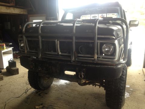 1970 Ford F-250 - Front view of a black Ford truck with a prominent grille guard and heavy-duty bumper, parked indoors.
