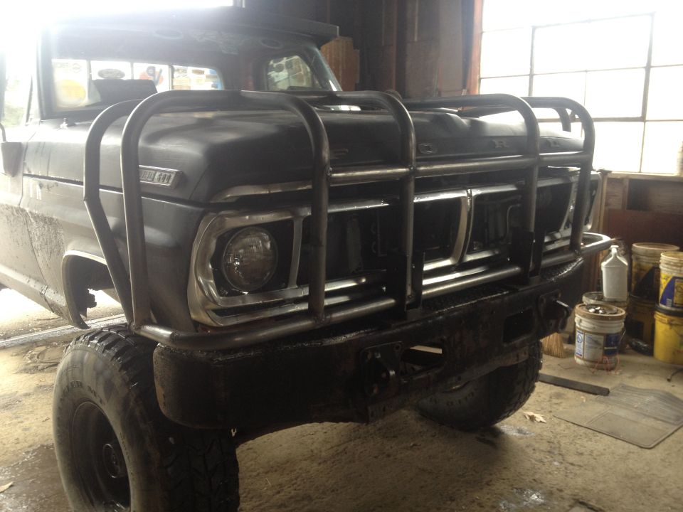 Front view of a black 1970 Ford F-250 with a custom bull bar and large tires
