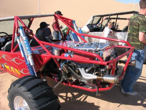 1993 Ford Taurus - A red dune buggy with a powerful engine sits on the sand, with another vehicle nearby.