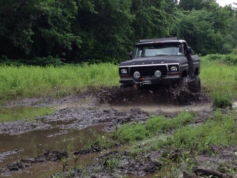 1979 Ford Bronco - This 1979 Ford Bronco is navigating a muddy trail with trees in the background.