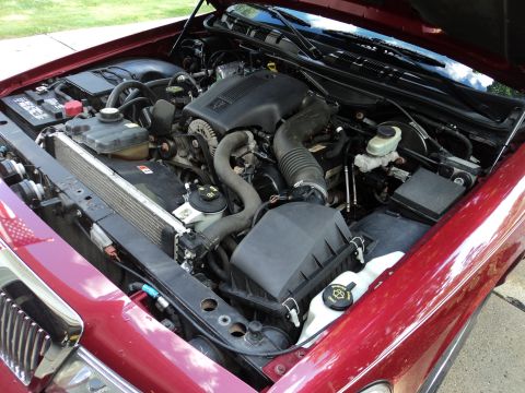 2004 Mercury Grand Marquis - The engine bay of a red 2004 Mercury Grand Marquis is shown with the hood open.