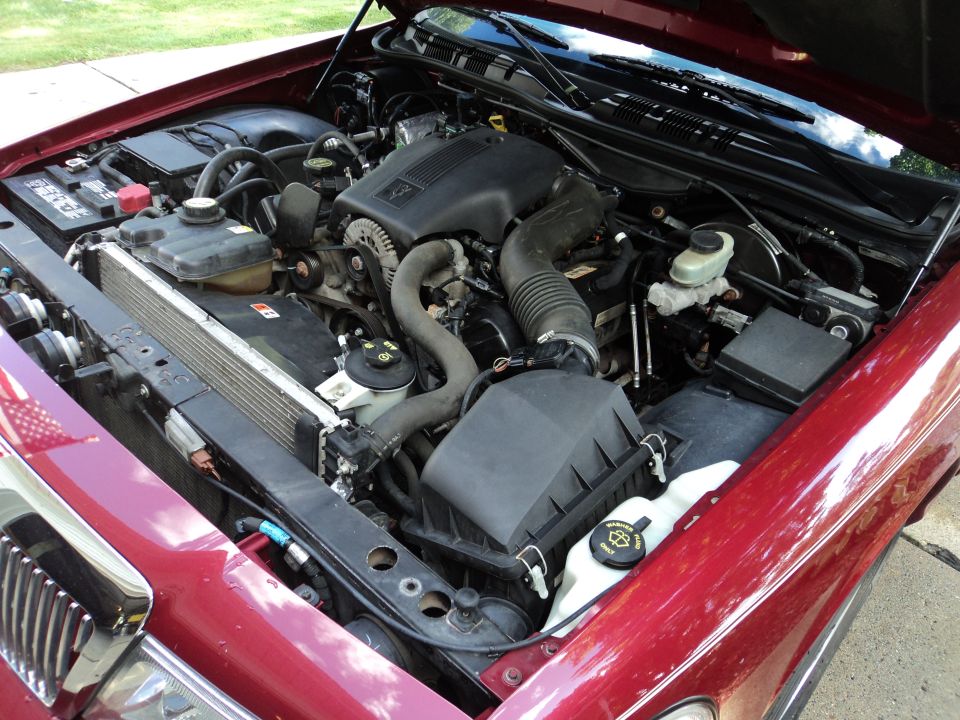 Red 2004 Mercury Grand Marquis engine bay with V8 engine, radiator, and battery visible