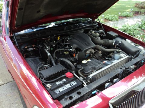 2004 Mercury Grand Marquis - The engine bay of a red 2004 Mercury Grand Marquis is shown with the hood open.