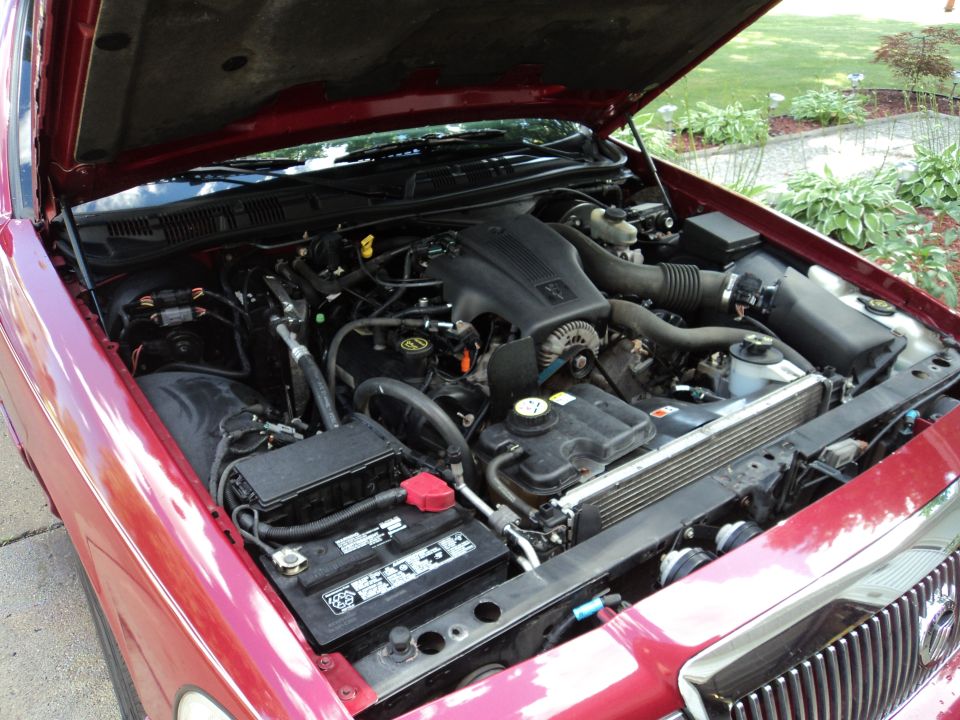 2004 Mercury Grand Marquis engine bay with hood open, showing V8 engine, battery, and radiator