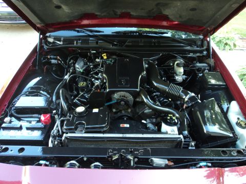 2004 Mercury Grand Marquis - The engine bay of a red 2004 Mercury Grand Marquis is shown with the hood open.