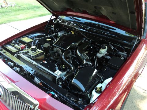 2004 Mercury Grand Marquis - The engine bay of a red 2004 Mercury Grand Marquis is shown with the hood open.