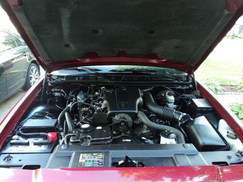 2004 Mercury Grand Marquis - The engine bay of a red 2004 Mercury Grand Marquis is visible with the hood raised.