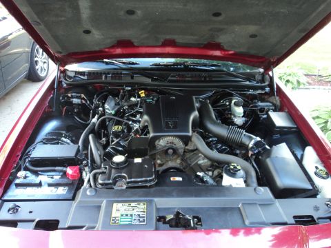 2004 Mercury Grand Marquis - The engine bay of a red 2004 Mercury Grand Marquis is visible with the hood raised.