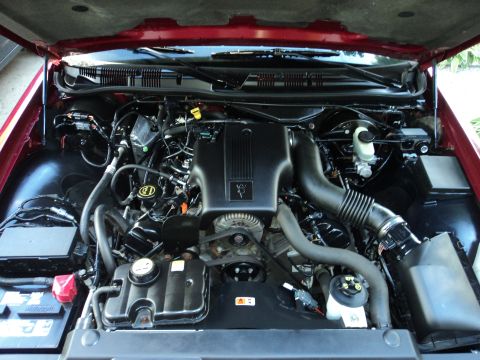 2004 Mercury Grand Marquis - The engine bay of a red 2004 Mercury Grand Marquis is shown, highlighting the V8 engine and associated components.