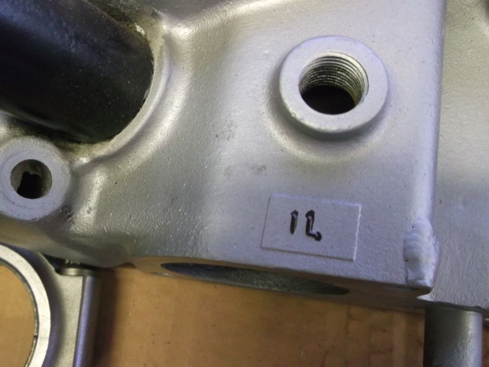 Aluminum engine component with threaded holes and a label marked '1L'