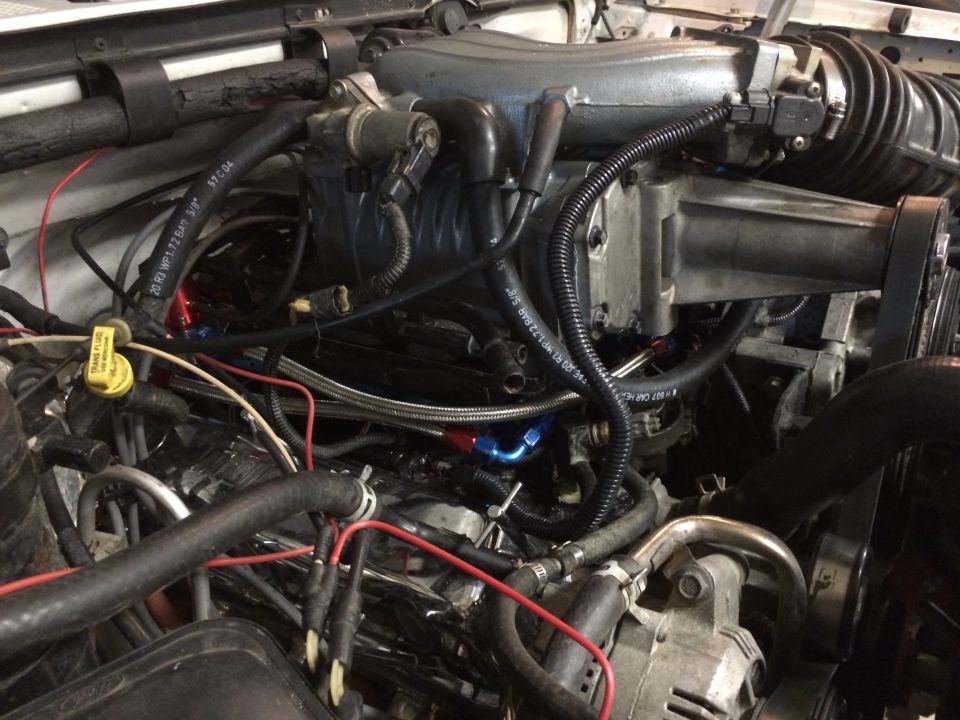 Engine bay with supercharger, hoses, and wiring visible. Supermotors.net logo in lower right