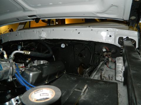 1979 Ford Bronco - Engine bay of a white vehicle with various components visible, including hoses, wiring, and a gauge.