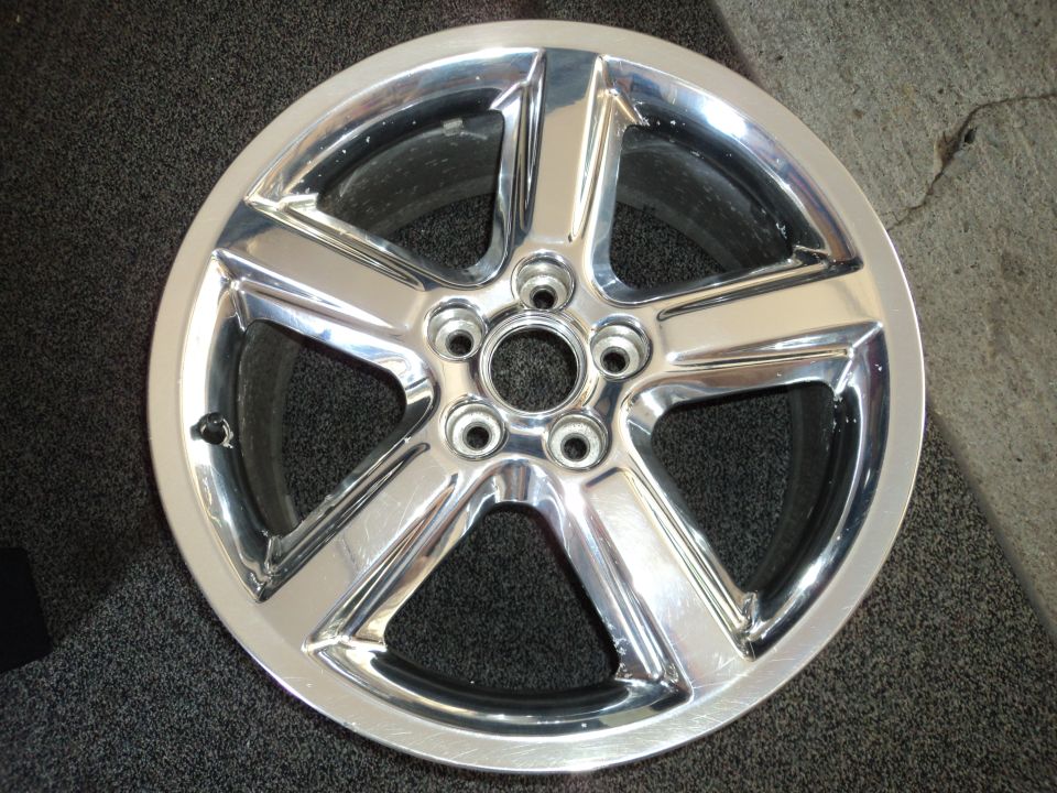 Chrome five-spoke wheel with five lug nut holes, showing minor scuffs