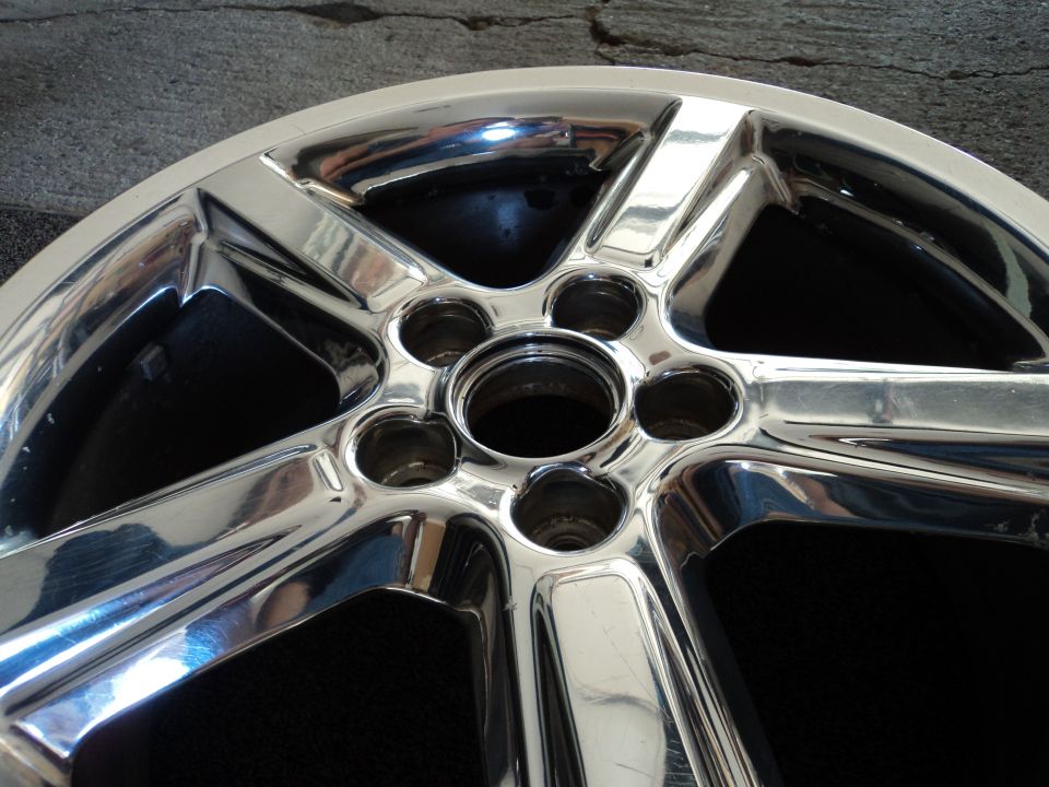 Close-up of a shiny chrome wheel with five spokes and lug nut holes