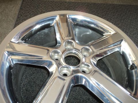 2004 Mercury Grand Marquis - A close-up view of a chrome wheel, showing its five-spoke design and lug nut mounting points.