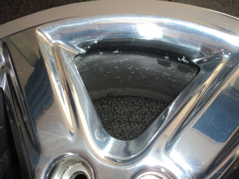 Chrome wheel with visible scratches and pitting, close-up view