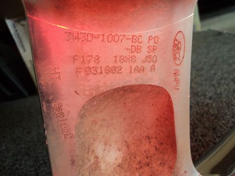 2004 Mercury Grand Marquis - This image shows a close-up of a vehicle wheel part with various stamped codes and a Ford logo visible.