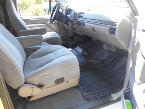 1994 Ford Bronco - The interior of a 1994 Ford Bronco, cloth seats, a dashboard with vents, and rubber floor mats.