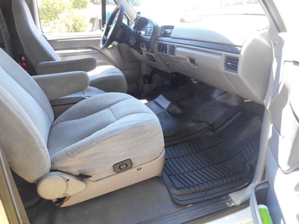 Interior of a 1994 Ford Bronco showing front seats, dashboard, and floor mats