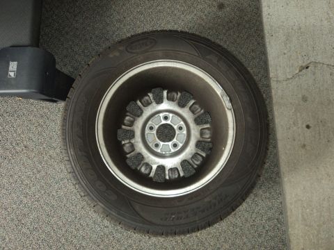 2004 Mercury Grand Marquis - A close-up view of a car's wheel and tire, with a black object to the left.