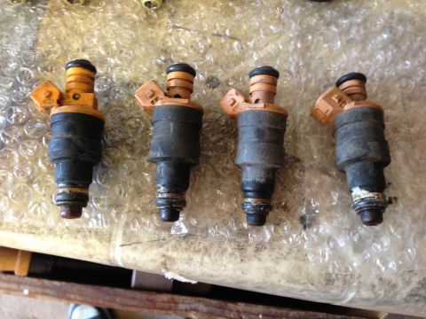 1989 Ford Bronco - A set of four used fuel injectors are shown, likely for a vehicle's engine.