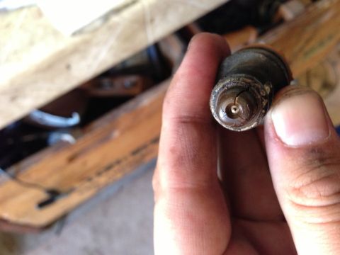 1989 Ford Bronco - A hand holds a used fuel injector, showing signs of wear and damage.