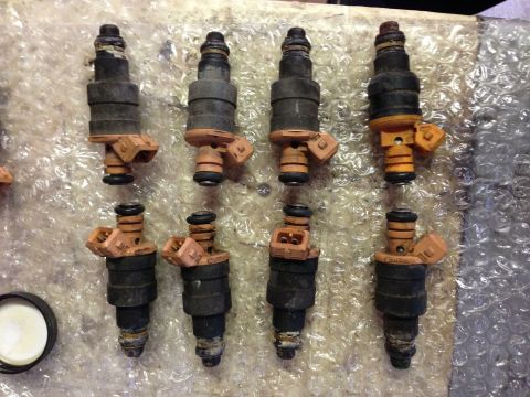 1989 Ford Bronco - A set of eight fuel injectors are displayed on a surface covered with bubble wrap.
