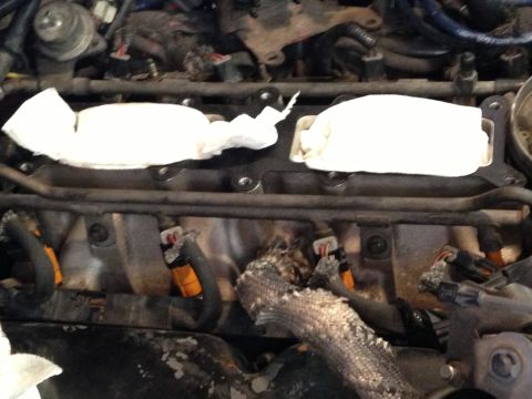 1989 Ford Bronco - Close-up of engine injectors and intake manifold, some parts covered with paper towels.