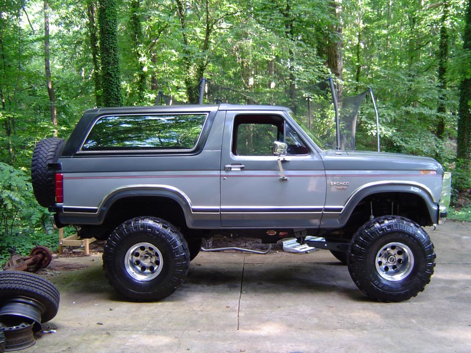 Lifted gray Ford Bronco with spare tire on back, parked outside