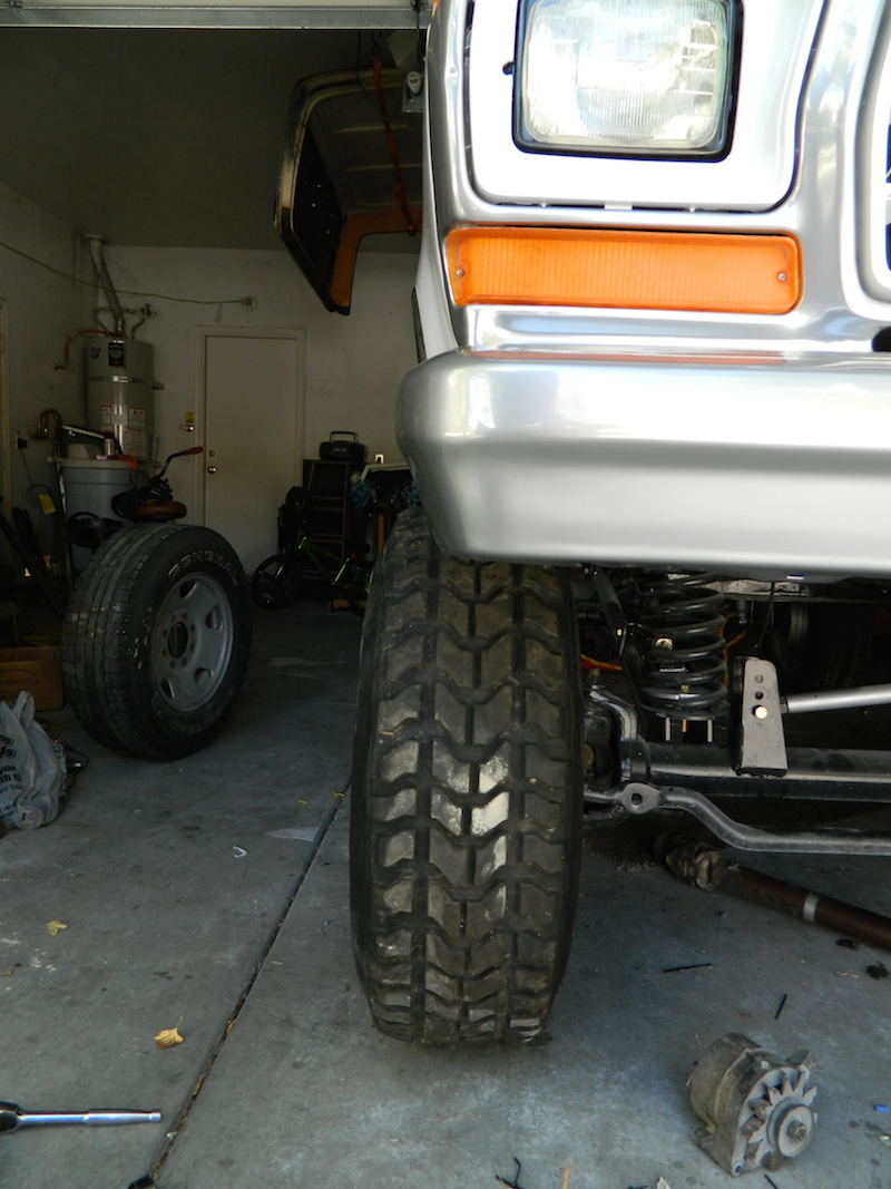 Front tire and suspension of a 1979 Ford Bronco in a garage