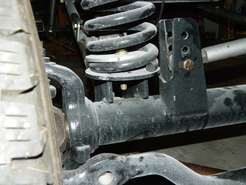 1979 Ford Bronco - Detail of a vehicle's front suspension system, showing a coil spring and mounting hardware.