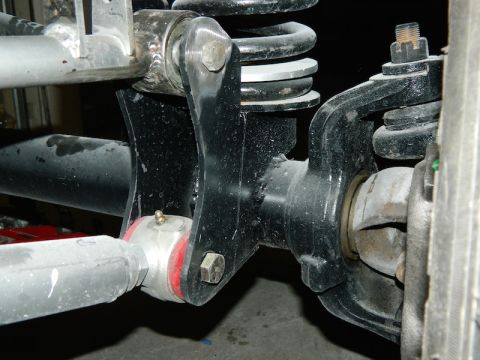 1979 Ford Bronco - Close-up view of a vehicle's suspension system, showing mechanical linkages and a coil spring.